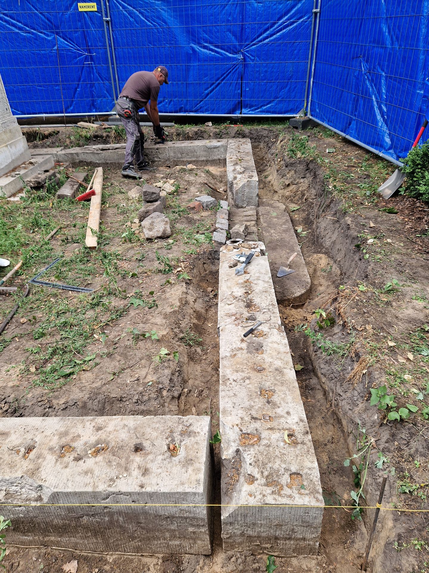 Dolomītakmens nožogojuma pamatnes bloki pirms bloku līmeņošanas asīs un akmens bloku protezēšanas
