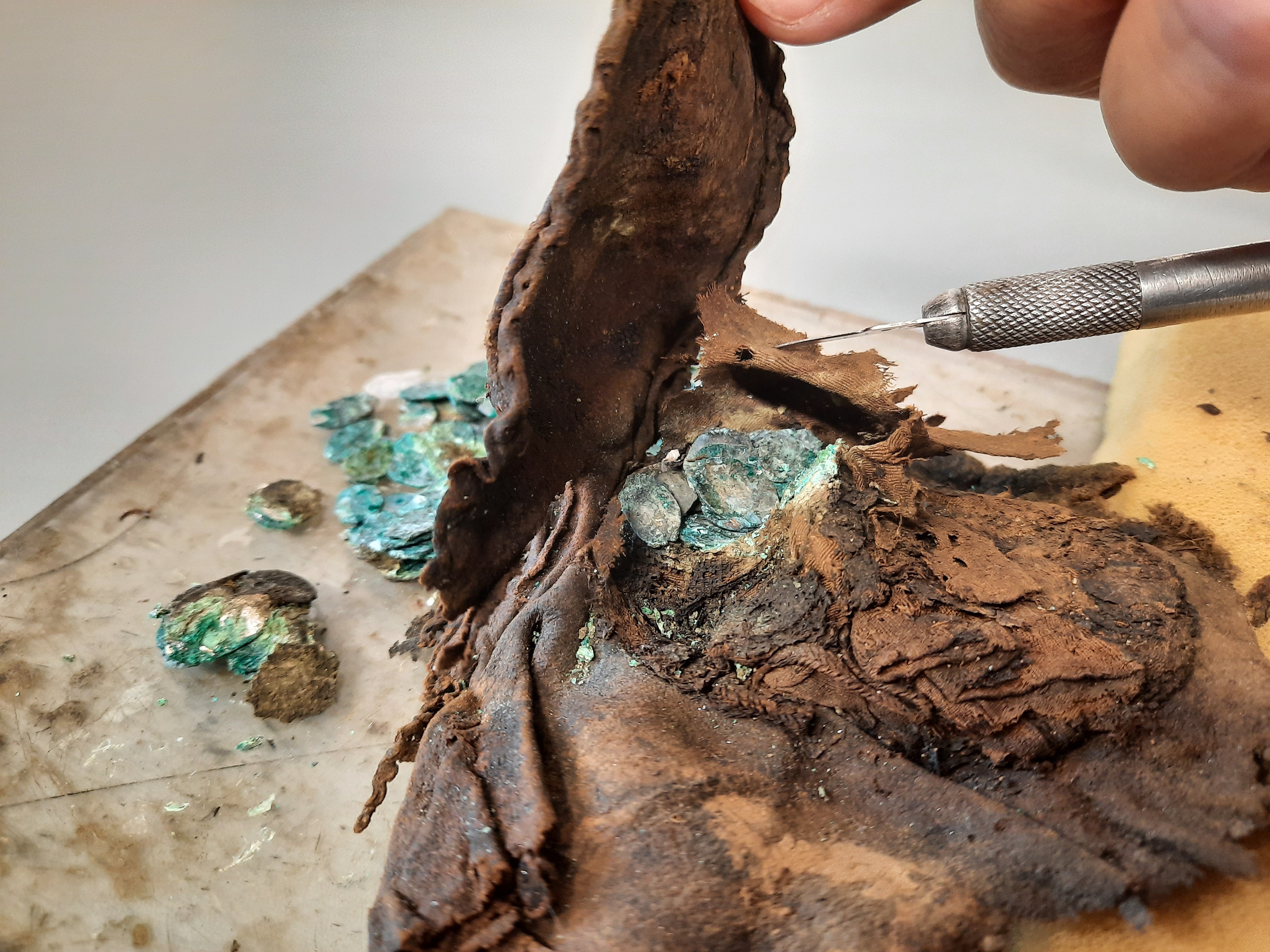 Ādas maks ar sudraba monētām restaurācijas procesā. Monētu izņemšana